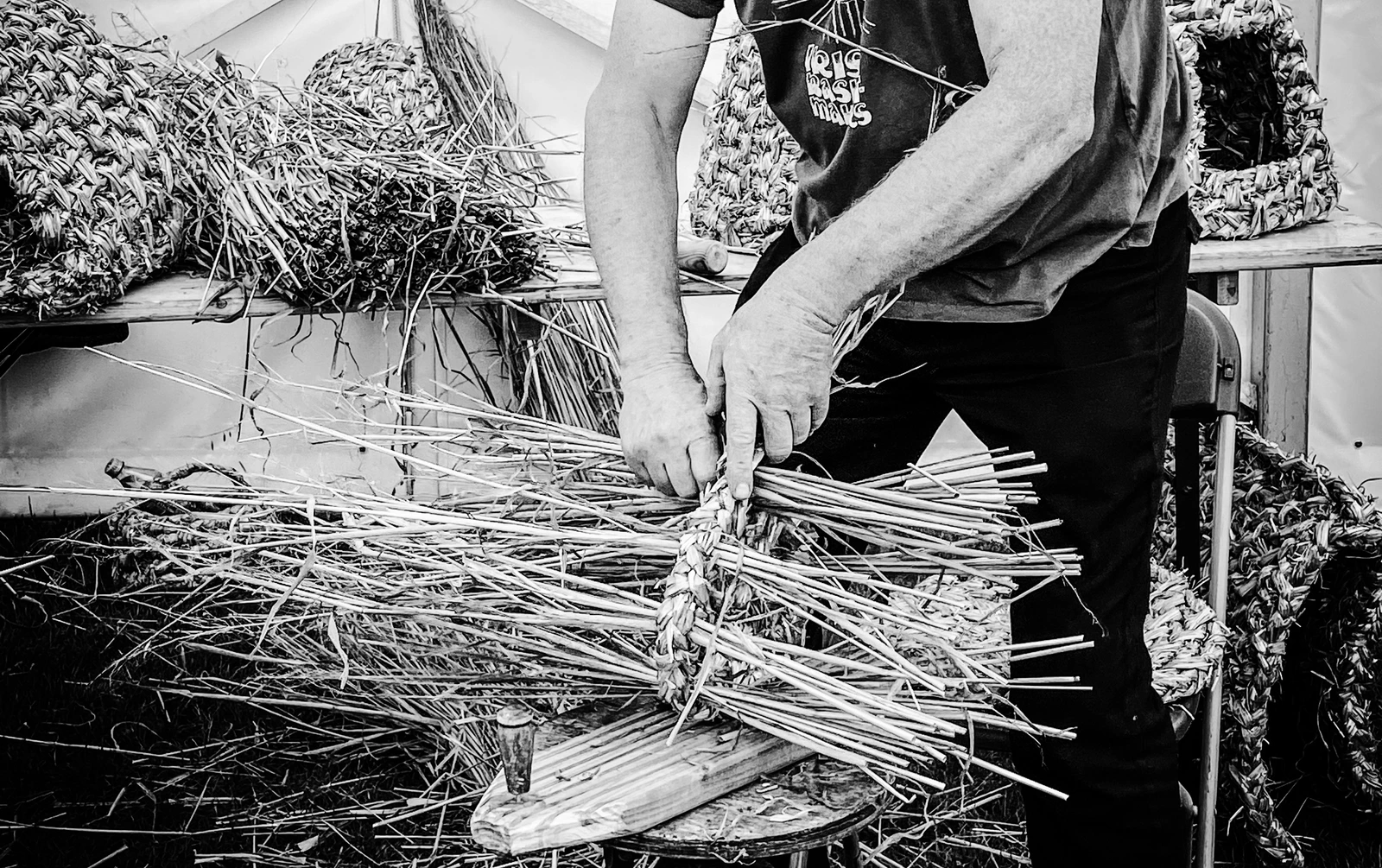 Hands weaving a traditional willow basket, photographed in Ireland.